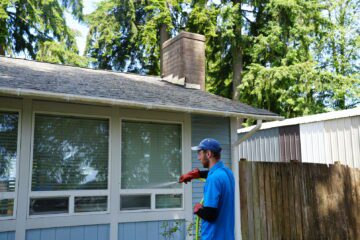 A Johnny Tsunami technician washes the siding of a house.